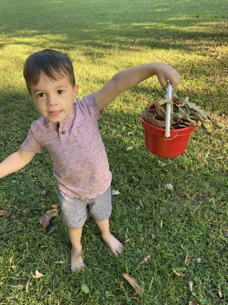 My son holding up his bucket of items he found on his autumn outdoor scavenger hunt
